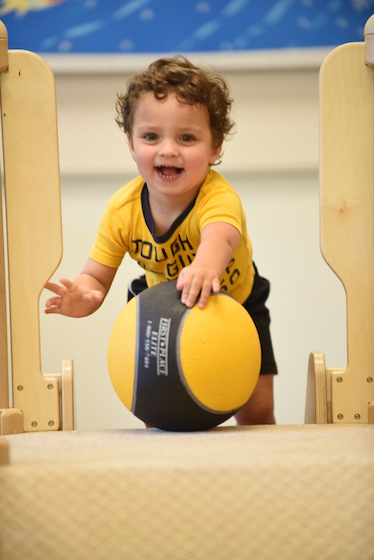 Toddler Matt Dillon, who attends The Summit Country Day School’s Montessori toddler program, rolls a ball down a slide, an activity that fosters development of gross motor skills and strength.